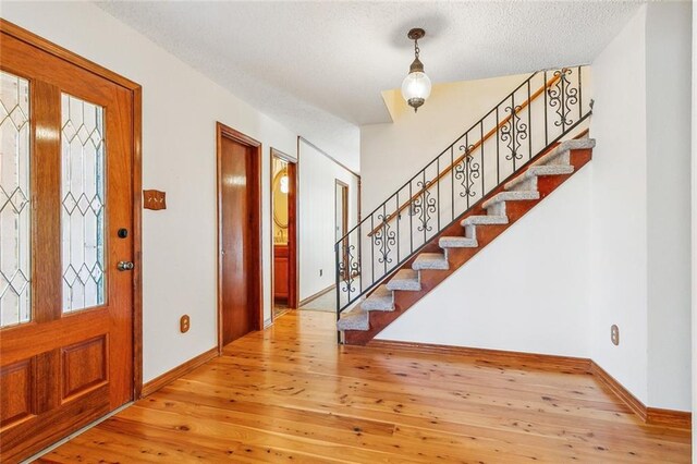 106 Somerset Rd, La Place, LA 70068 - foyer with wood-type flooring, baseboards, a textured ceiling, and stairs