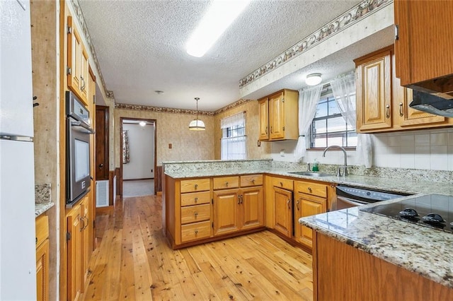 106 Somerset Rd, La Place, LA 70068 - kitchen featuring light wood-type flooring, a peninsula, a textured ceiling, appliances with stainless steel finishes, and a sink