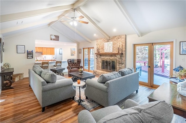 living area with light wood-style floors, french doors, ceiling fan, and vaulted ceiling with beams