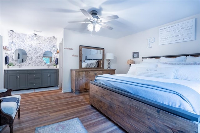 bedroom featuring wood finished floors, ensuite bathroom, and ceiling fan