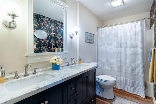 full bath with a sink, toilet, double vanity, and wood finished floors