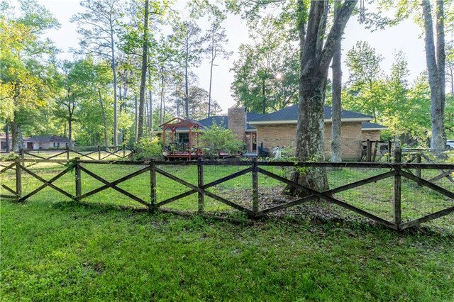 view of gate with fence and a lawn