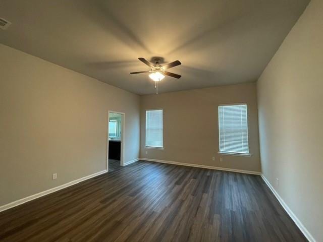 empty room with ceiling fan, dark wood finished floors, and baseboards