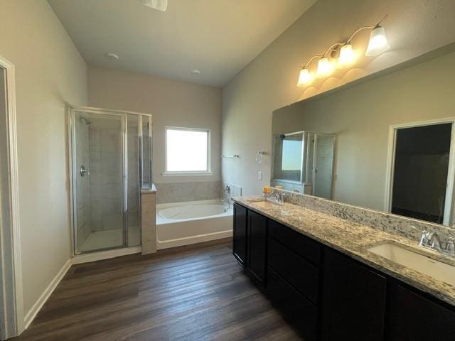 full bath with a sink, a shower stall, a bath, double vanity, and wood finished floors