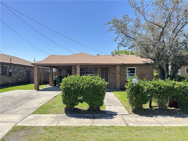 single story home featuring a front yard, a carport, brick siding, driveway, and roof with shingles