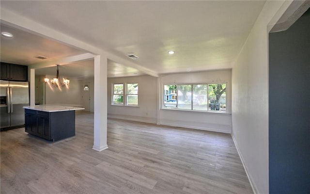 unfurnished living room featuring visible vents, baseboards, a notable chandelier, light wood-type flooring, and recessed lighting