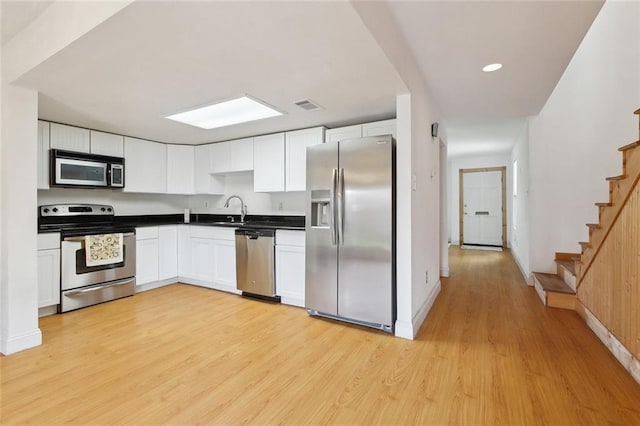 kitchen featuring dark countertops, white cabinets, light wood-style floors, visible vents, and stainless steel appliances