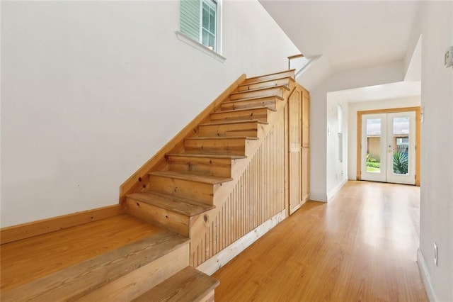 stairs featuring wood finished floors, baseboards, and a wealth of natural light