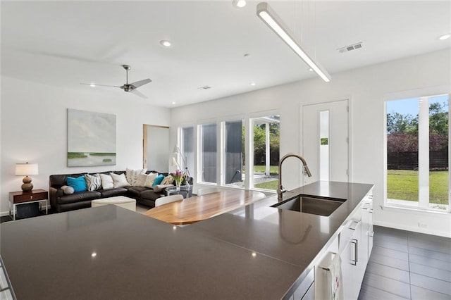 60209 Pine Dr, Lacombe, LA 70445 - kitchen featuring a sink, a wealth of natural light, dark countertops, and white cabinetry