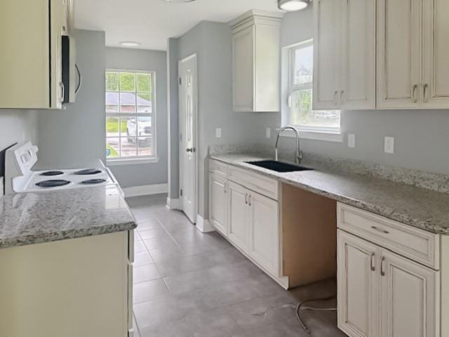 kitchen featuring white range with electric stovetop, a sink, stainless steel microwave, and light stone countertops