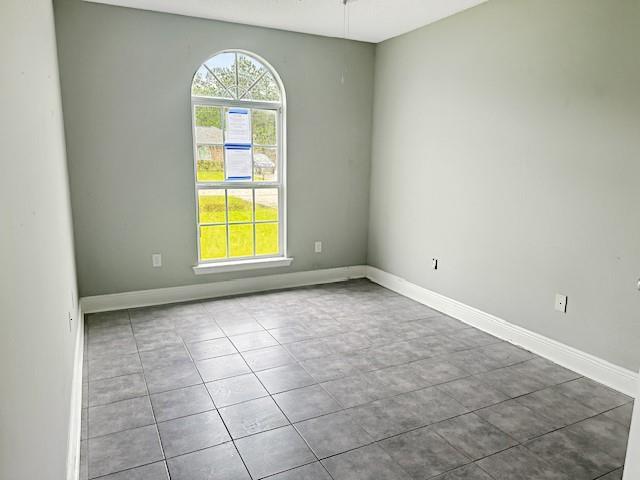 unfurnished room with tile patterned floors and baseboards