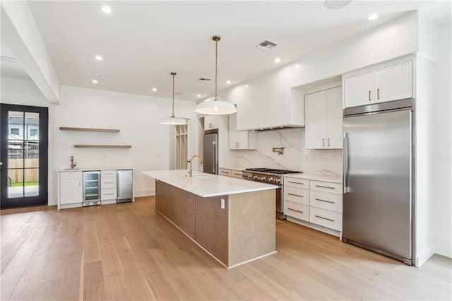 6371 Louis Xiv St, New Orleans, LA 70124 - kitchen with premium appliances, beverage cooler, light countertops, light wood-style floors, and tasteful backsplash