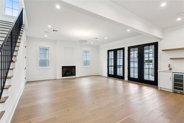 6371 Louis Xiv St, New Orleans, LA 70124 - unfurnished living room with wine cooler, stairs, light wood-type flooring, recessed lighting, and bar with sink