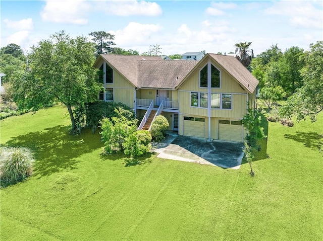 rear view of property featuring driveway, stairs, a porch, a garage, and a lawn