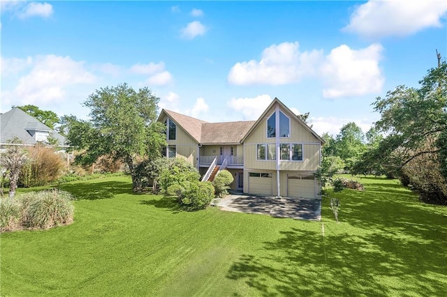 rear view of property with an attached garage, a yard, driveway, and stairway
