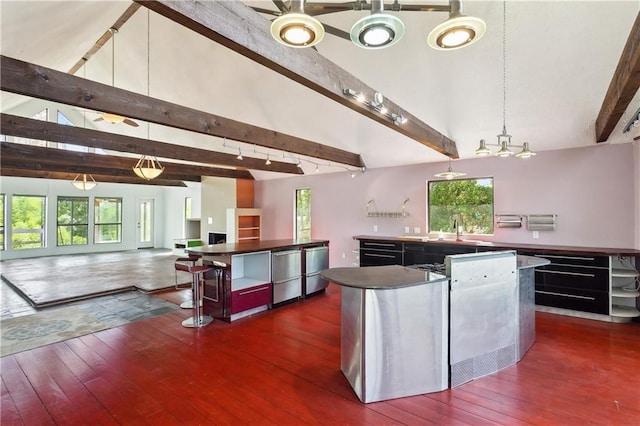 kitchen with a center island, a sink, open floor plan, hardwood / wood-style flooring, and vaulted ceiling with beams