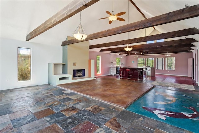 living room featuring stone tile flooring, beam ceiling, high vaulted ceiling, and ceiling fan