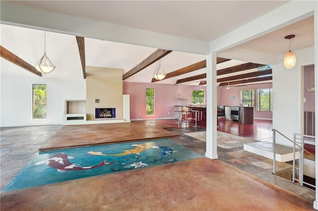 interior space with concrete floors, baseboards, vaulted ceiling with beams, and a fireplace