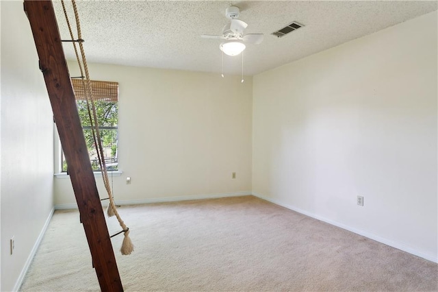 spare room with a textured ceiling, visible vents, ceiling fan, and carpet