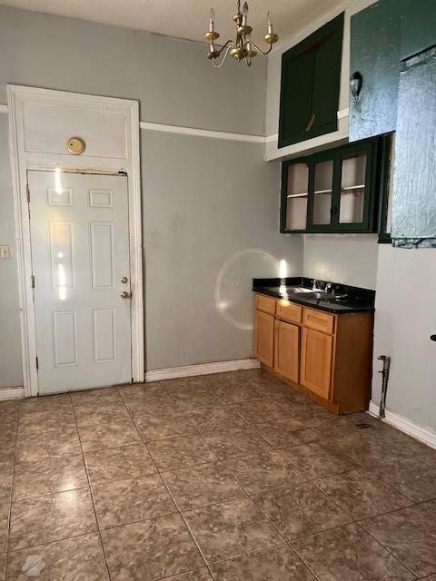 275755 Toulouse St, New Orleans, LA 70119 - interior space featuring dark tile patterned floors, baseboards, a chandelier, dark countertops, and a sink
