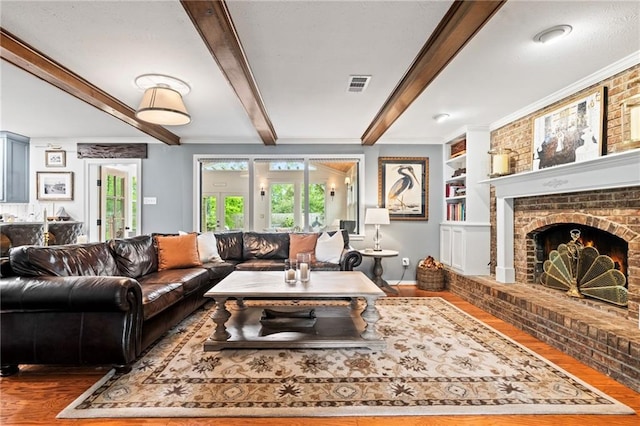 616 Marilyn Dr, Mandeville, LA 70448 - living area with beamed ceiling, a fireplace, visible vents, wood finished floors, and built in shelves