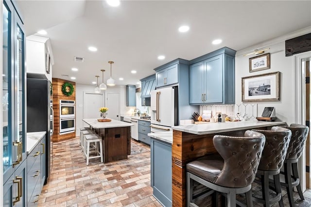 616 Marilyn Dr, Mandeville, LA 70448 - kitchen featuring visible vents, light countertops, white appliances, a kitchen bar, and a peninsula