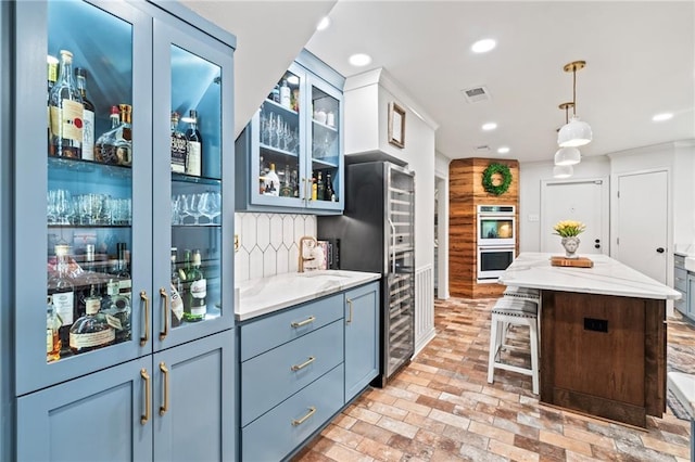 616 Marilyn Dr, Mandeville, LA 70448 - kitchen with freestanding refrigerator, glass insert cabinets, double oven, decorative light fixtures, and brick floor