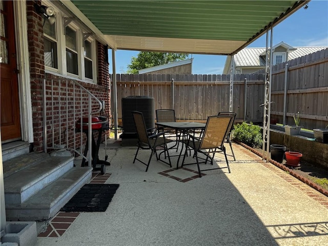 view of patio featuring entry steps, outdoor dining space, central AC unit, and fence
