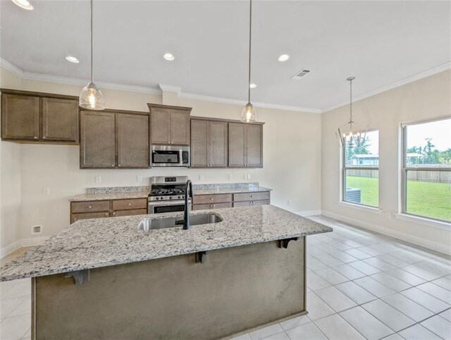 9508 E Terran Ln, Waggaman, LA 70094 - kitchen with appliances with stainless steel finishes, a breakfast bar area, a chandelier, a kitchen island with sink, and light stone counters