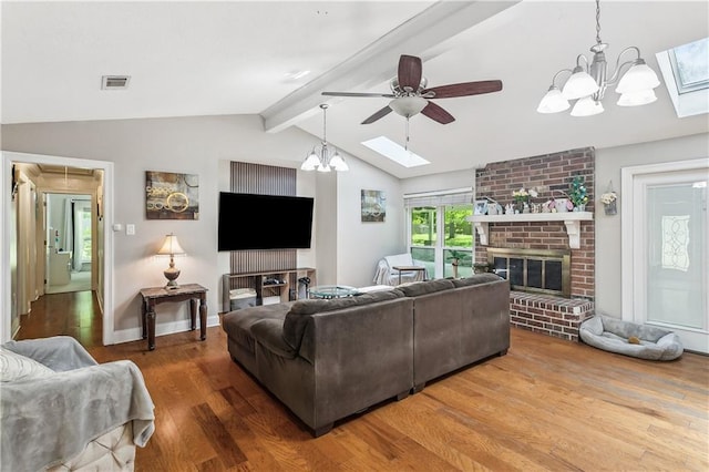 123 Fischer Dr, Pearl River, LA 70452 - living area with wood finished floors, visible vents, a fireplace, vaulted ceiling with skylight, and ceiling fan with notable chandelier