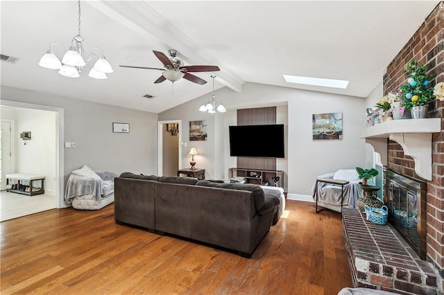 123 Fischer Dr, Pearl River, LA 70452 - living area featuring lofted ceiling with skylight, wood finished floors, ceiling fan with notable chandelier, a fireplace, and visible vents
