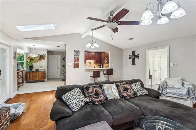 123 Fischer Dr, Pearl River, LA 70452 - living room with ceiling fan with notable chandelier, lofted ceiling with skylight, visible vents, and light wood-style flooring