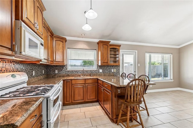 1601 Carthage Dr, Marrero, LA 70072 - kitchen featuring a sink, brown cabinetry, white appliances, light tile patterned floors, and a peninsula