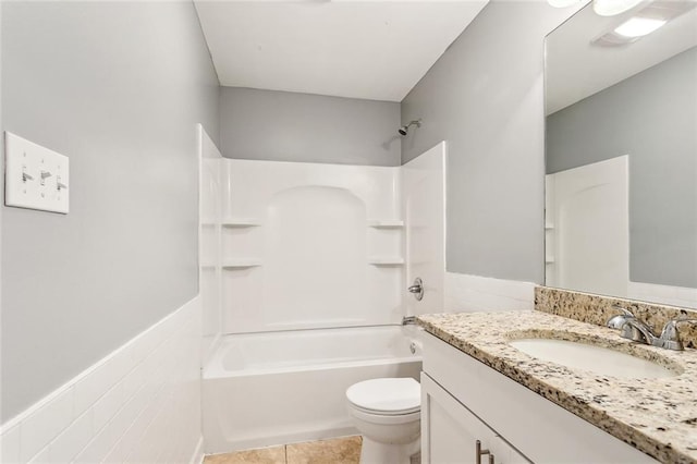 full bathroom featuring tile patterned floors, bathing tub / shower combination, a wainscoted wall, toilet, and vanity