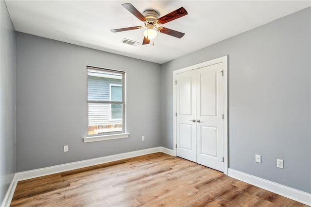 unfurnished bedroom with a ceiling fan, wood finished floors, a closet, baseboards, and visible vents
