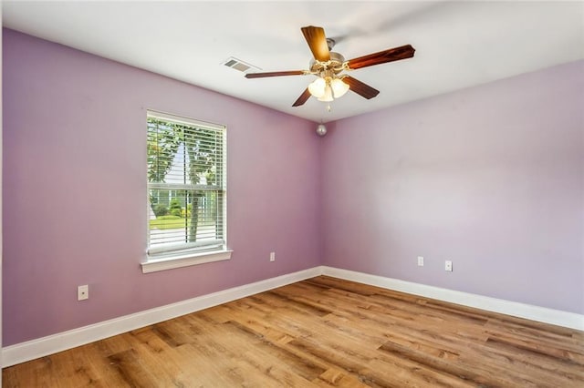 empty room with baseboards, wood finished floors, visible vents, and a ceiling fan