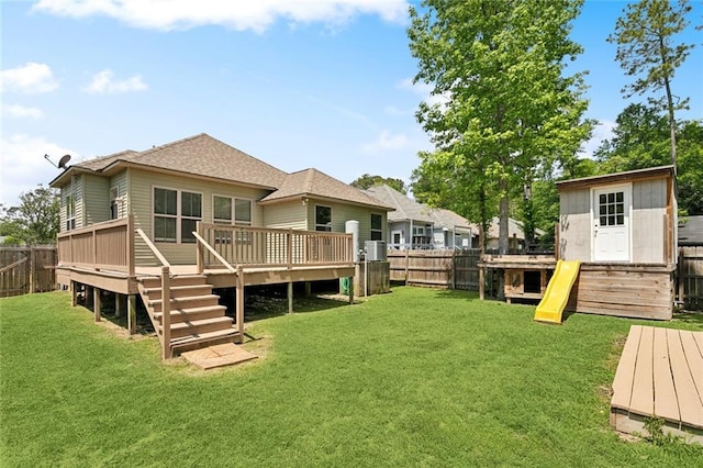 rear view of house featuring a fenced backyard, a yard, a deck, and a shingled roof