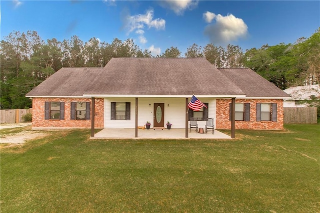 rear view of house featuring brick siding, fence, a yard, and a patio