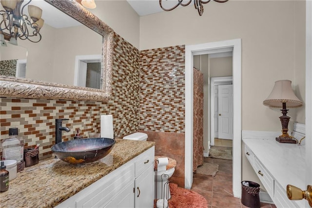 full bath with tile patterned floors, vanity, tile walls, backsplash, and a notable chandelier