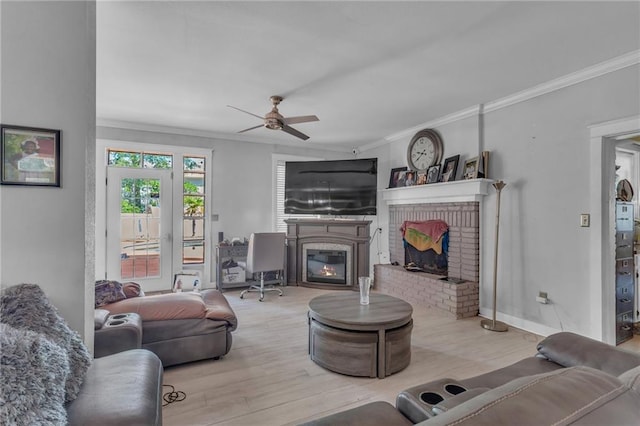 living room featuring ceiling fan, ornamental molding, a brick fireplace, and wood finished floors