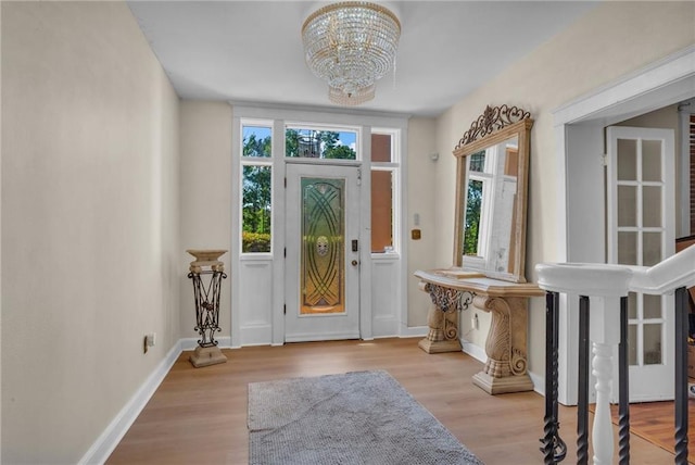 entryway featuring baseboards, wood finished floors, a chandelier, and plenty of natural light