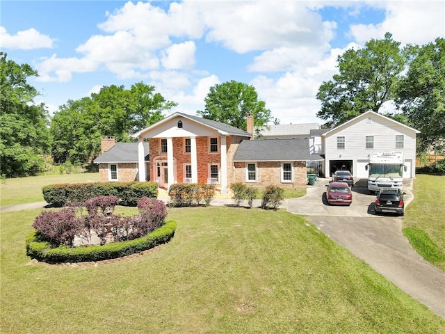 neoclassical / greek revival house with a garage, a chimney, driveway, a front yard, and brick siding