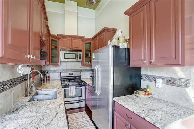 1323 Esplanade Ave Unit C, New Orleans, LA 70116 - kitchen featuring appliances with stainless steel finishes, a sink, backsplash, light stone counters, and glass insert cabinets