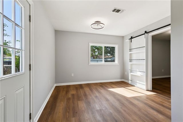 1929 Kentucky Ave, Kenner, LA 70062 - unfurnished bedroom with baseboards, wood finished floors, visible vents, and a barn door