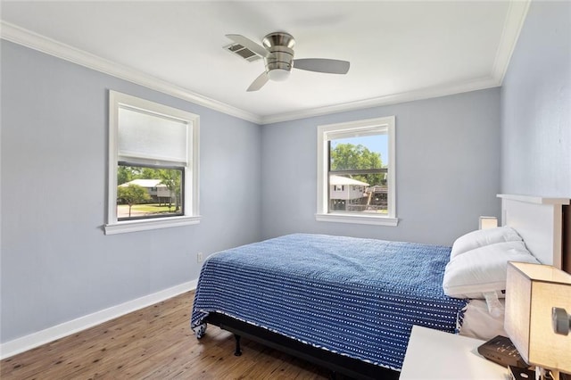 bedroom with baseboards, ornamental molding, wood finished floors, and visible vents