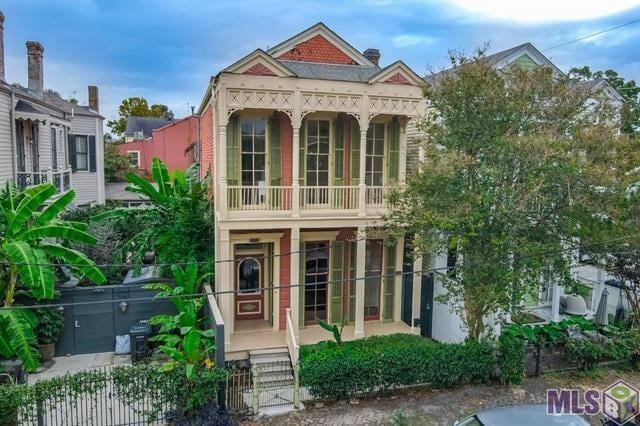 view of front facade featuring a porch, fence, and a balcony