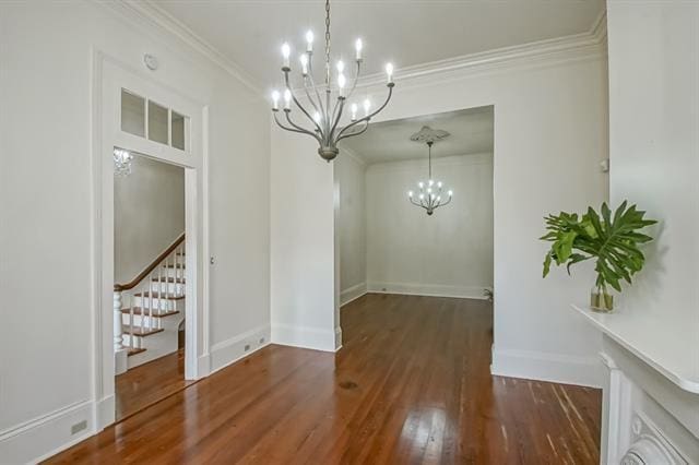 unfurnished dining area with visible vents, an inviting chandelier, wood finished floors, stairs, and ornamental molding