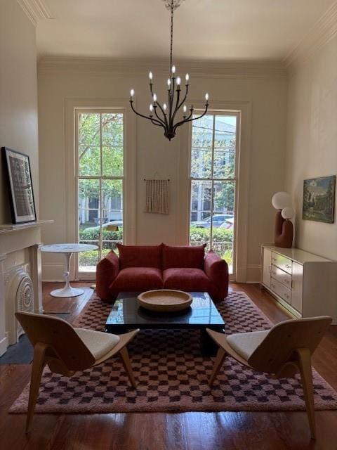living area featuring a chandelier, wood finished floors, crown molding, and baseboards
