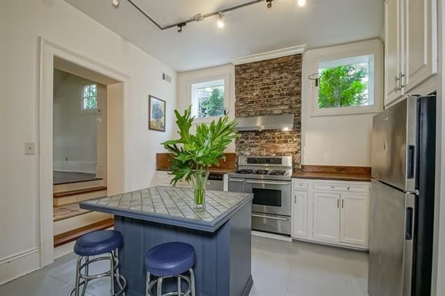 kitchen featuring white cabinets, stainless steel appliances, a breakfast bar, and extractor fan