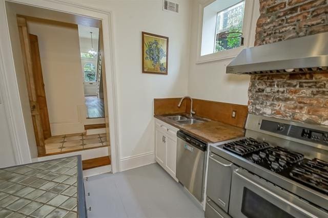kitchen with a sink, plenty of natural light, visible vents, exhaust hood, and appliances with stainless steel finishes